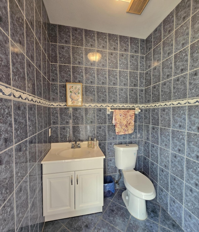 bathroom with tile patterned floors, vanity, tile walls, and toilet