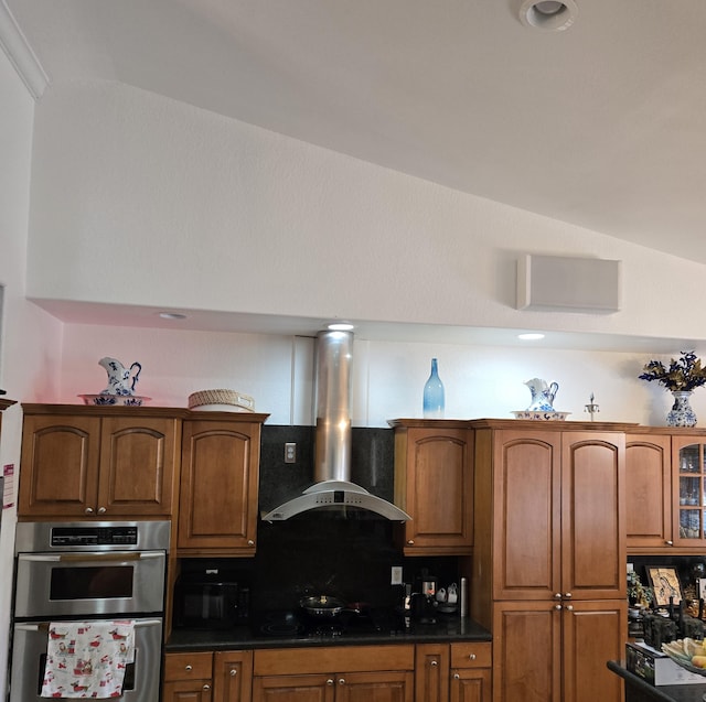 kitchen featuring black appliances, wall chimney exhaust hood, backsplash, and dark stone counters