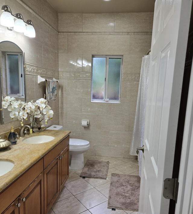 bathroom with toilet, vanity, tile patterned floors, and tile walls