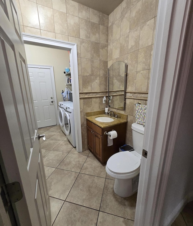 bathroom with vanity, tile patterned floors, toilet, washing machine and dryer, and tile walls