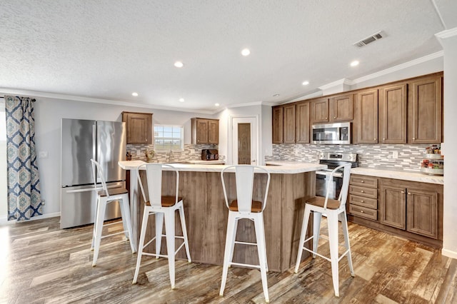 kitchen featuring a center island, a kitchen breakfast bar, hardwood / wood-style flooring, tasteful backsplash, and stainless steel appliances