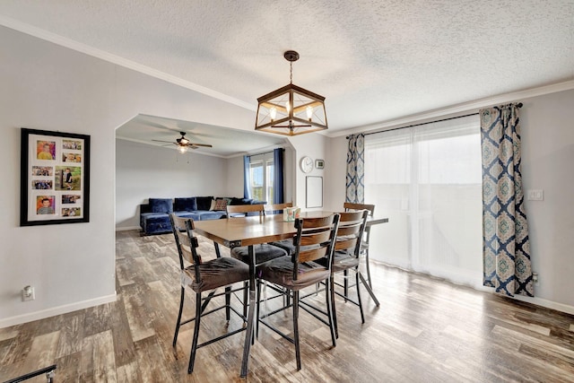 dining space featuring ceiling fan with notable chandelier, ornamental molding, a textured ceiling, and hardwood / wood-style flooring