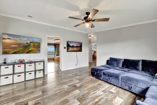 living room featuring ceiling fan, ornamental molding, a textured ceiling, and light hardwood / wood-style flooring