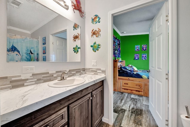 bathroom with vanity, wood-type flooring, backsplash, and ornamental molding