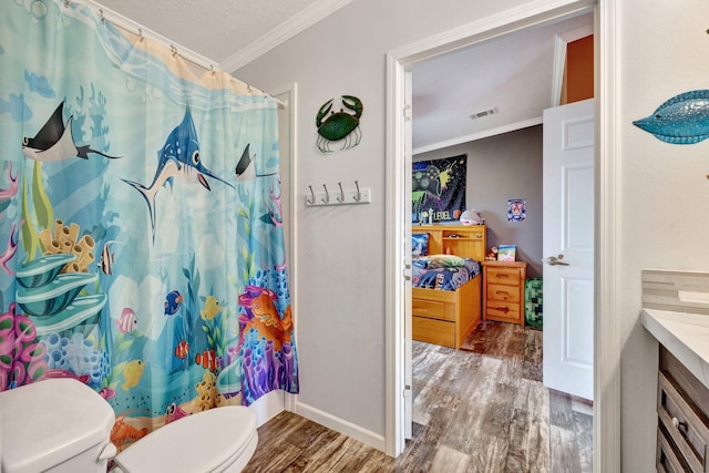 bathroom featuring crown molding, hardwood / wood-style floors, vanity, and toilet