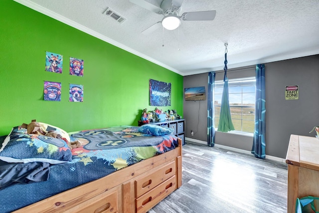 bedroom with ceiling fan, light hardwood / wood-style floors, ornamental molding, and a textured ceiling