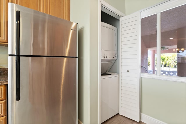 laundry room with light hardwood / wood-style floors and stacked washer and dryer