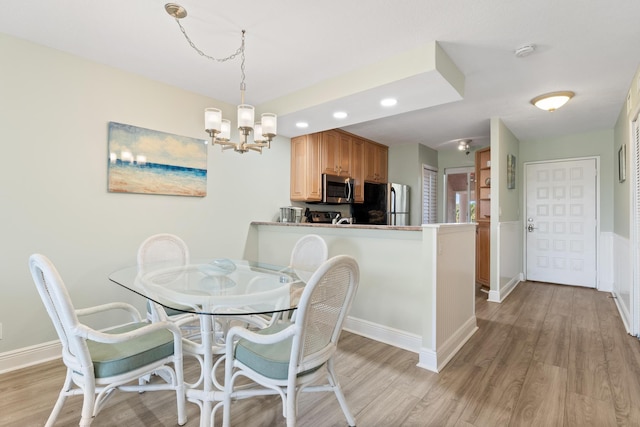 dining area with light hardwood / wood-style flooring and a notable chandelier