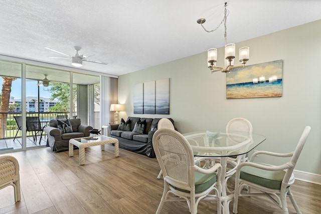 dining space featuring hardwood / wood-style flooring, ceiling fan with notable chandelier, floor to ceiling windows, and a textured ceiling