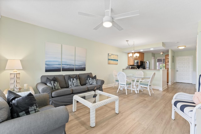 living room with ceiling fan with notable chandelier and light wood-type flooring