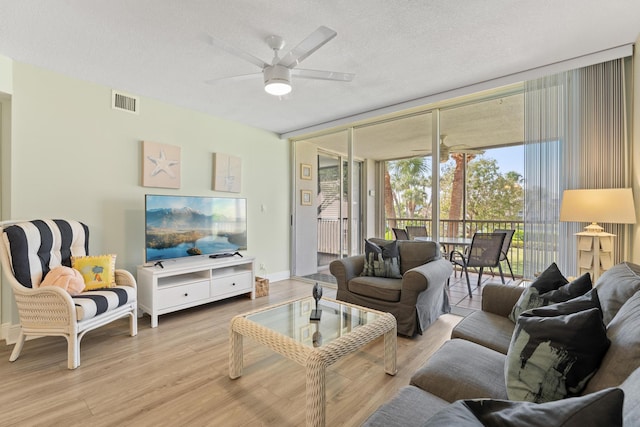 living room featuring floor to ceiling windows, ceiling fan, a textured ceiling, and light wood-type flooring