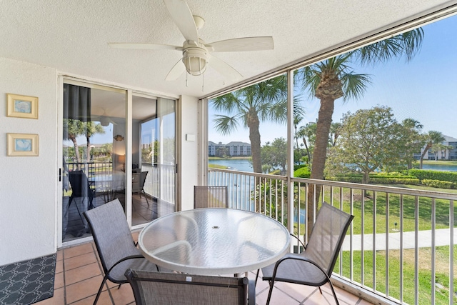 sunroom with ceiling fan and a water view