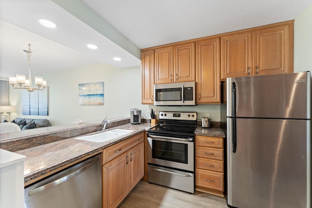 kitchen with an inviting chandelier, sink, dark stone countertops, light wood-type flooring, and stainless steel appliances