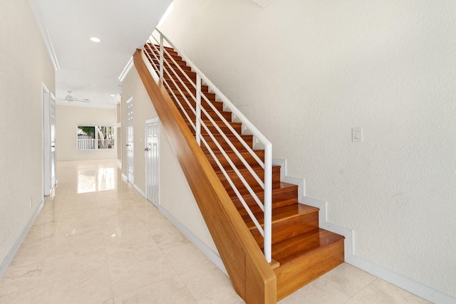 stairway featuring ceiling fan