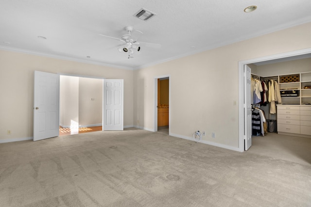 unfurnished bedroom with ceiling fan, ornamental molding, light carpet, a walk in closet, and a closet