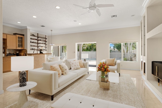 living room featuring ceiling fan, ornamental molding, and a textured ceiling