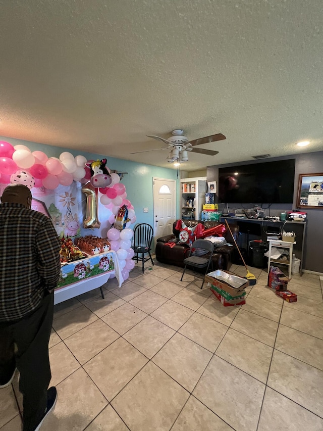 bedroom featuring ceiling fan, light tile patterned flooring, and a textured ceiling