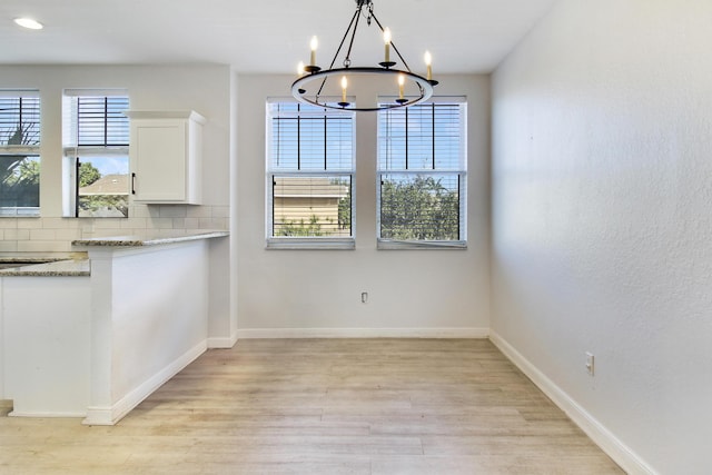 unfurnished dining area featuring light hardwood / wood-style flooring and a notable chandelier