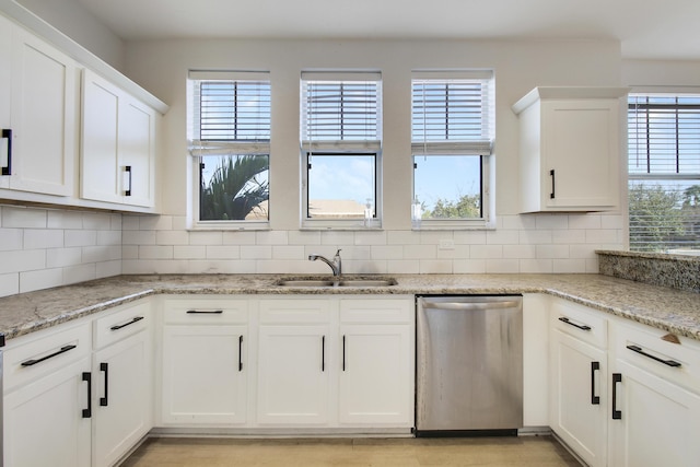 kitchen featuring white cabinets, backsplash, stainless steel dishwasher, and light stone counters