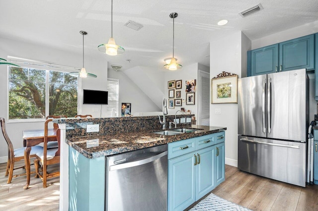 kitchen featuring sink, blue cabinets, hanging light fixtures, and appliances with stainless steel finishes