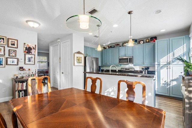 dining space featuring sink, light wood-type flooring, and a textured ceiling