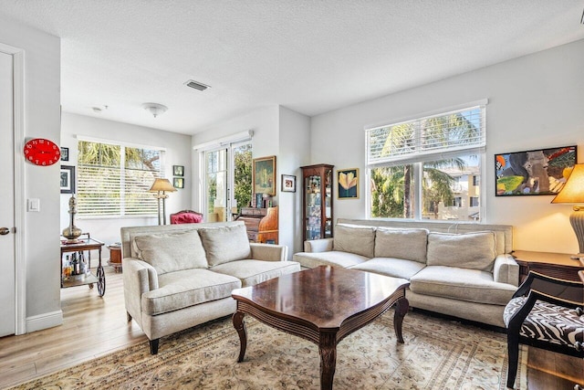 living room featuring french doors, a textured ceiling, and light hardwood / wood-style floors