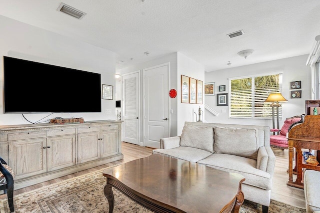 living room featuring a textured ceiling and light hardwood / wood-style flooring