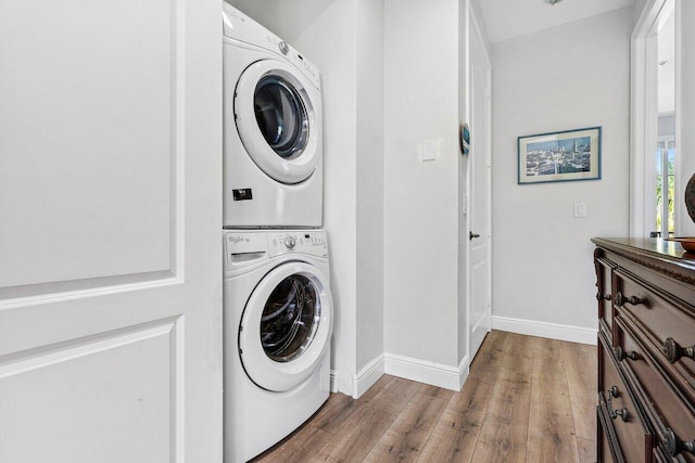 laundry area with stacked washer / drying machine and hardwood / wood-style flooring