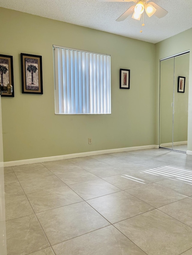 spare room with ceiling fan, a textured ceiling, and light tile patterned flooring