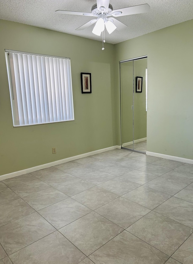 spare room featuring light tile patterned flooring, ceiling fan, and a textured ceiling