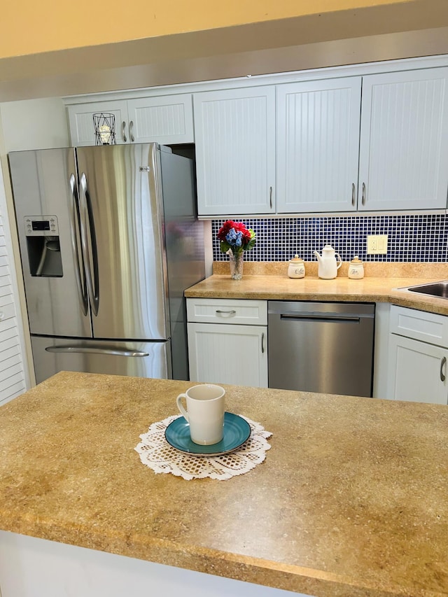 kitchen featuring appliances with stainless steel finishes, sink, white cabinets, and decorative backsplash