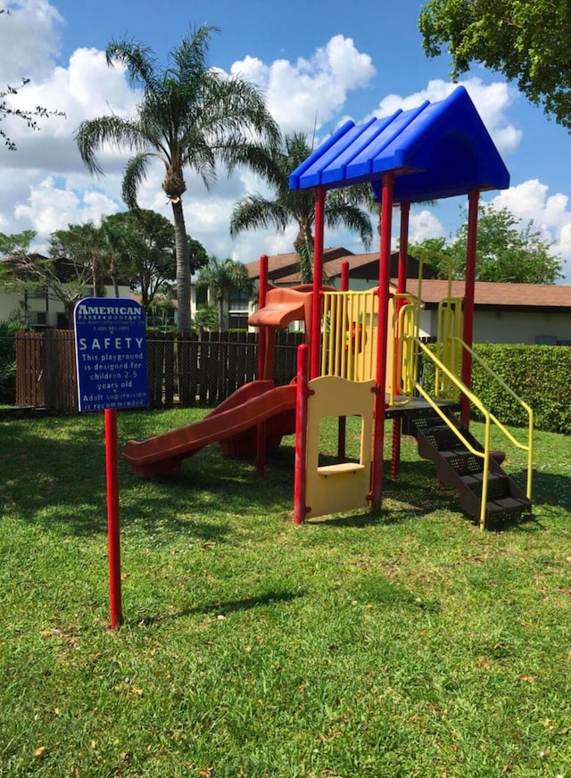 community play area with a lawn and fence