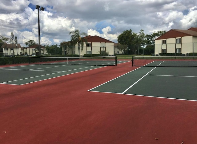 view of tennis court featuring community basketball court and fence