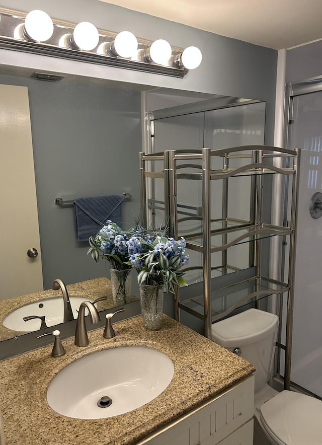 bathroom with a shower with door, vanity, and toilet