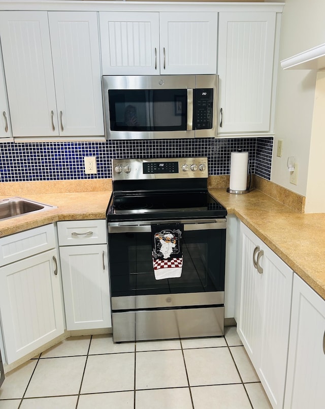 kitchen with sink, white cabinetry, stainless steel appliances, tasteful backsplash, and light tile patterned flooring