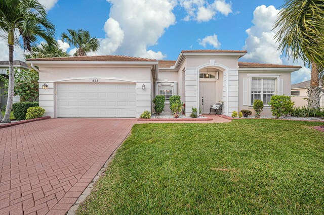 mediterranean / spanish home featuring a garage and a front lawn