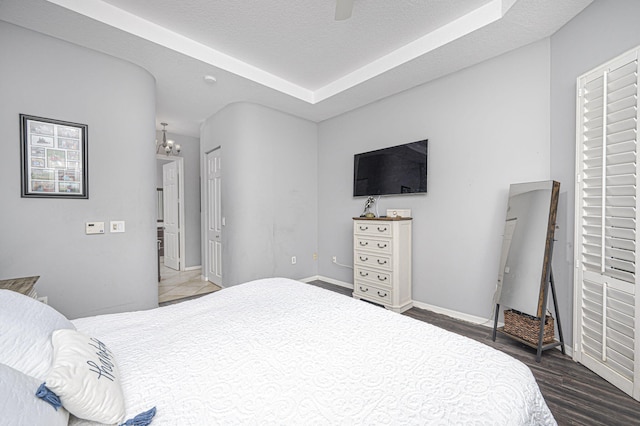 bedroom with a textured ceiling, dark hardwood / wood-style floors, and ceiling fan with notable chandelier