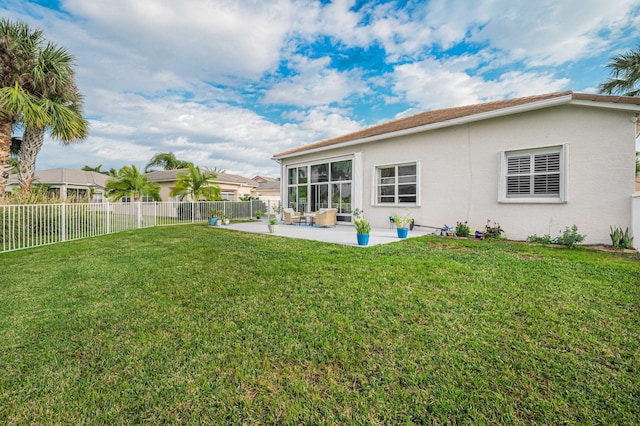 rear view of property featuring a yard and a patio area