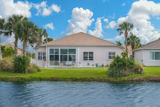 rear view of house with a water view and a yard