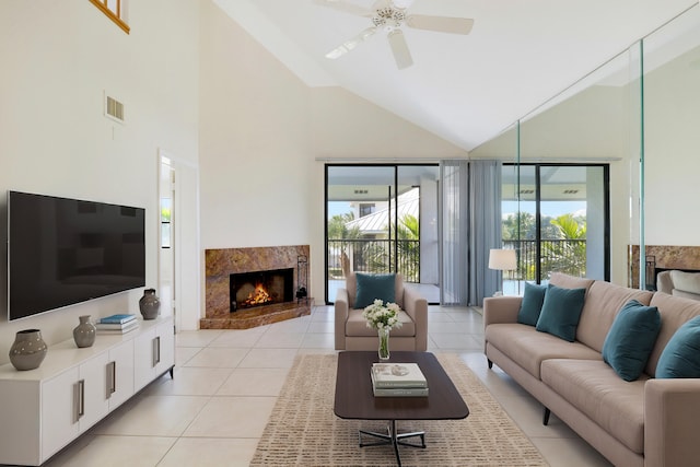 tiled living room featuring a high end fireplace, ceiling fan, and high vaulted ceiling