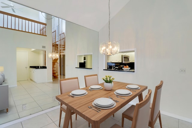 tiled dining space with ceiling fan with notable chandelier and high vaulted ceiling