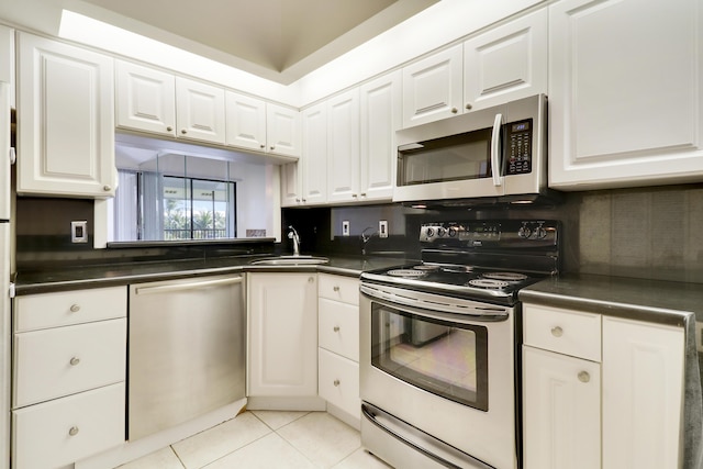 kitchen with light tile patterned flooring, sink, white cabinets, and stainless steel appliances