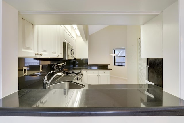 kitchen with kitchen peninsula, sink, white cabinets, and appliances with stainless steel finishes