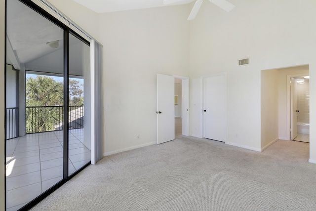 carpeted empty room with ceiling fan and high vaulted ceiling