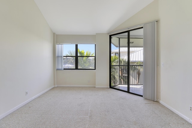 carpeted empty room featuring vaulted ceiling