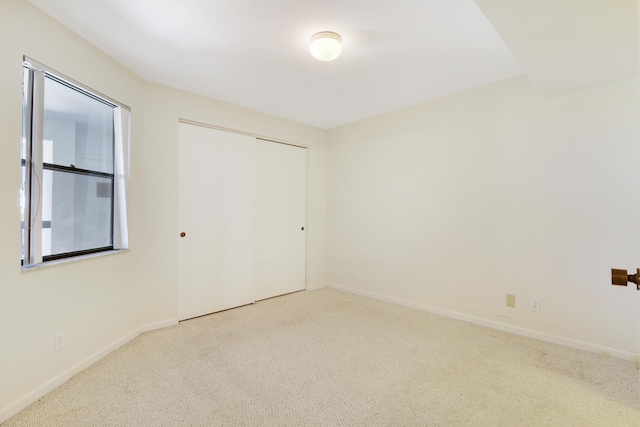 unfurnished bedroom with light colored carpet and a closet