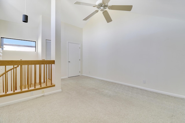 empty room featuring ceiling fan, high vaulted ceiling, and light colored carpet