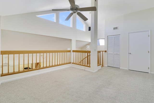 carpeted empty room featuring ceiling fan, plenty of natural light, and high vaulted ceiling