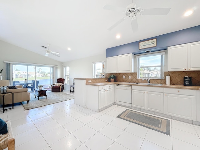 kitchen featuring dishwasher, white cabinets, sink, vaulted ceiling, and decorative backsplash