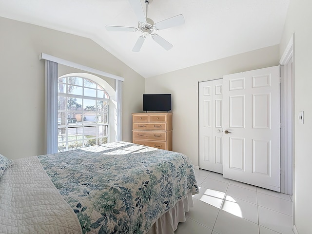 bedroom featuring ceiling fan, light tile patterned flooring, lofted ceiling, and a closet